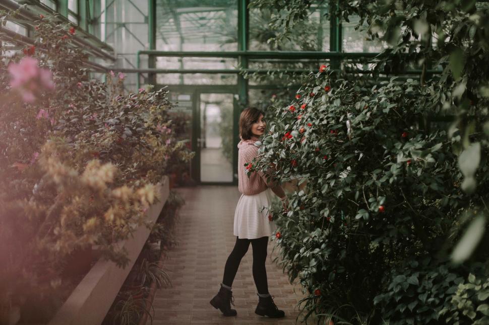 Free Image of Playful woman twirling in a botanical garden 