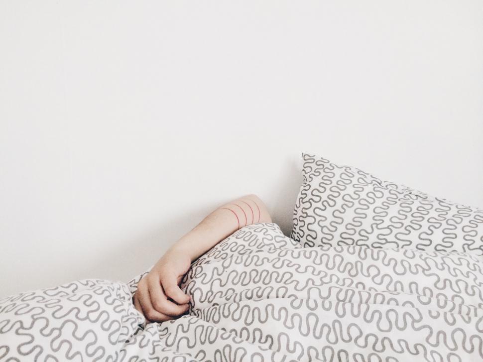 Free Image of Hand peeking out from patterned bedding 
