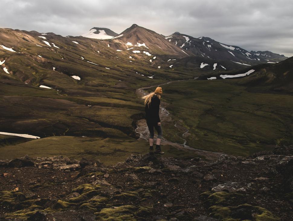 Free Image of Hiker overlooking green valley and mountains 