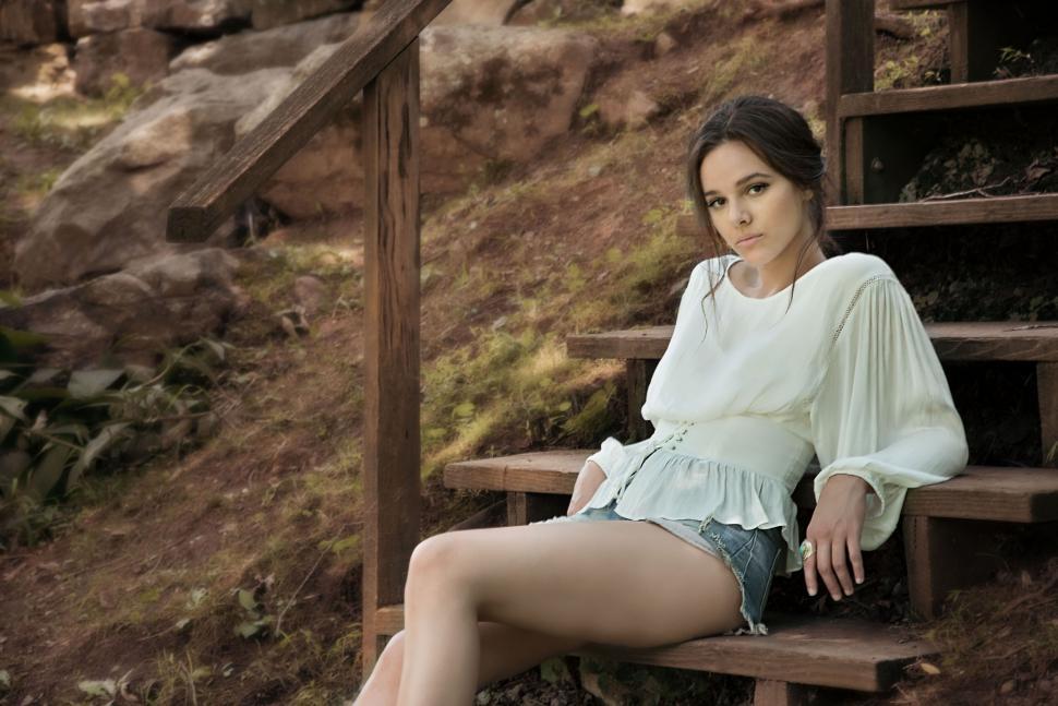 Free Image of Woman sitting on wooden stairs in nature 