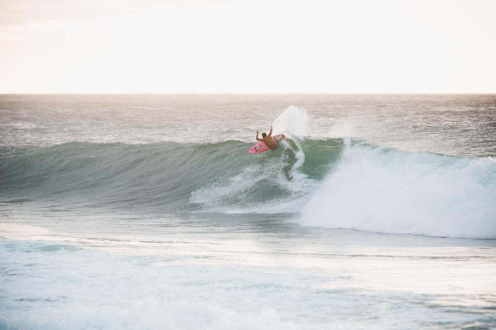 Free Image of Surfer riding a wave during sunset 