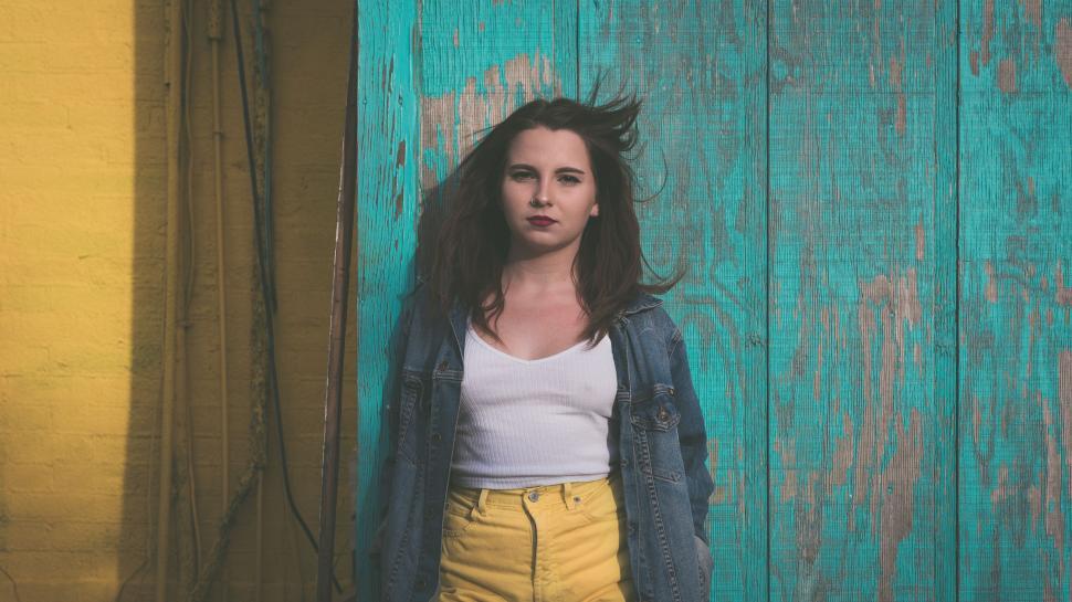 Free Image of Woman against vibrant turquoise wall 