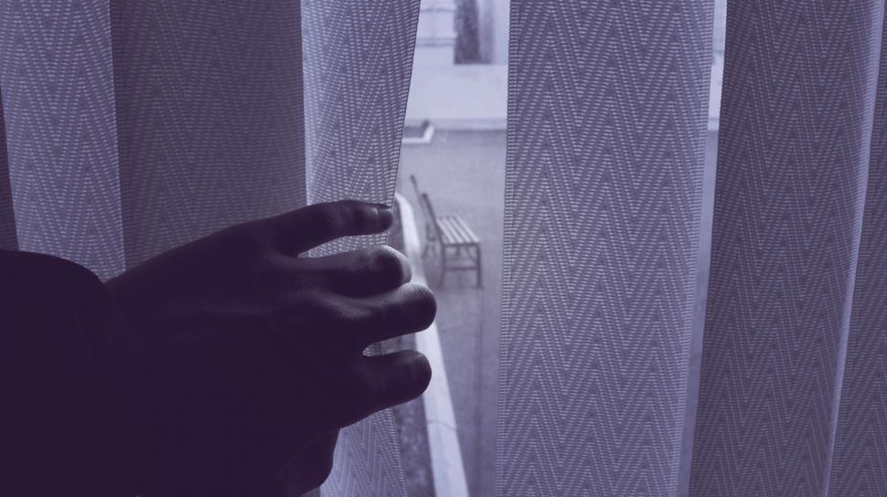 Free Image of Hand parting white curtains looking out 
