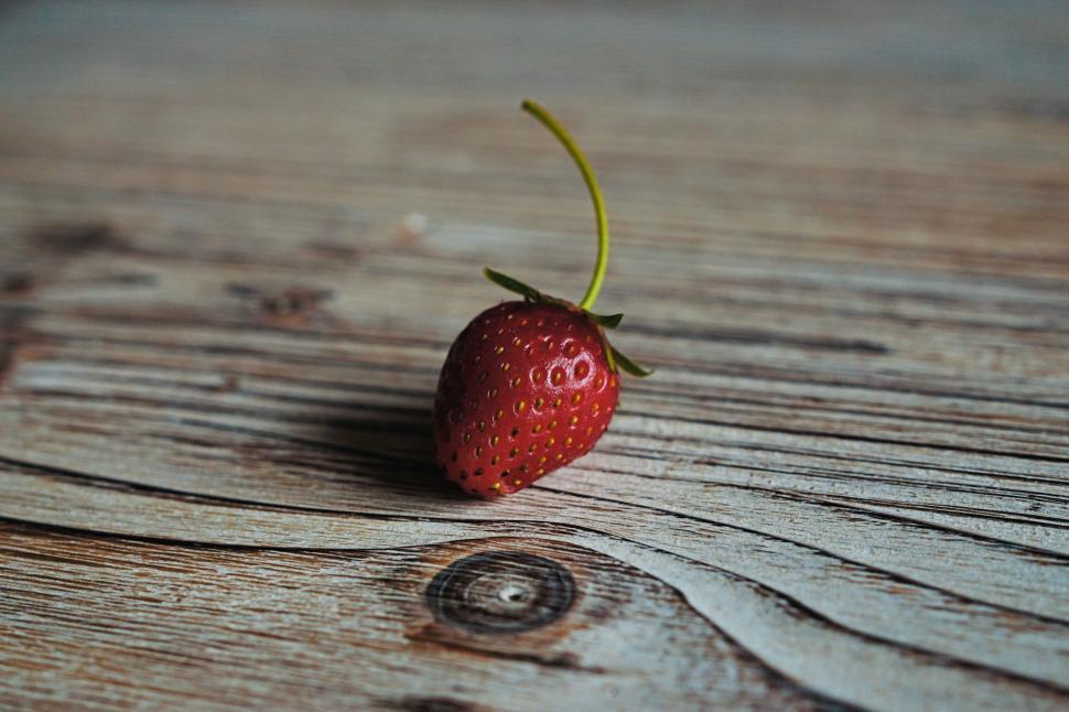 Free Image of Single strawberry on rustic wooden board 