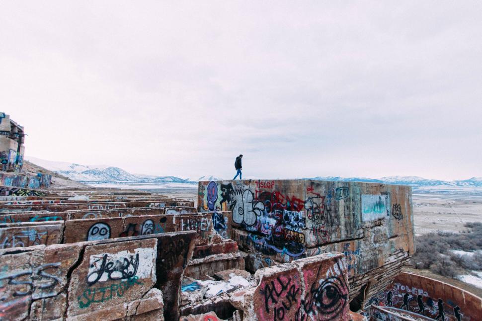 Free Image of Person observing graffiti atop snow-covered ruins 