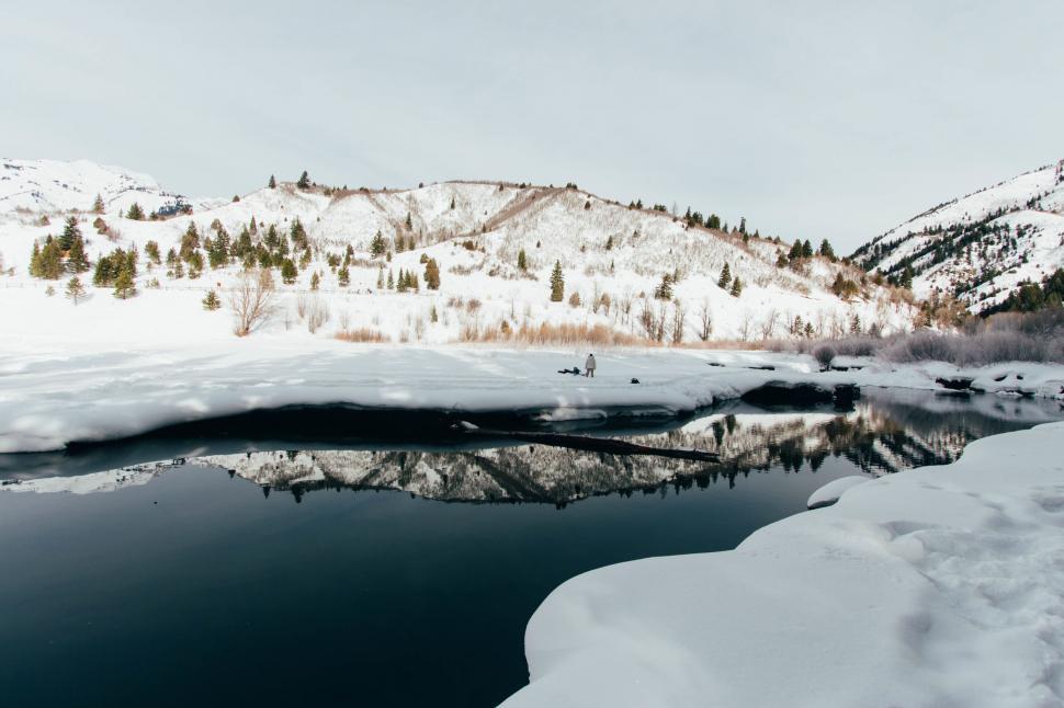 Free Image of Reflection of snowy hills in a calm frozen lake 