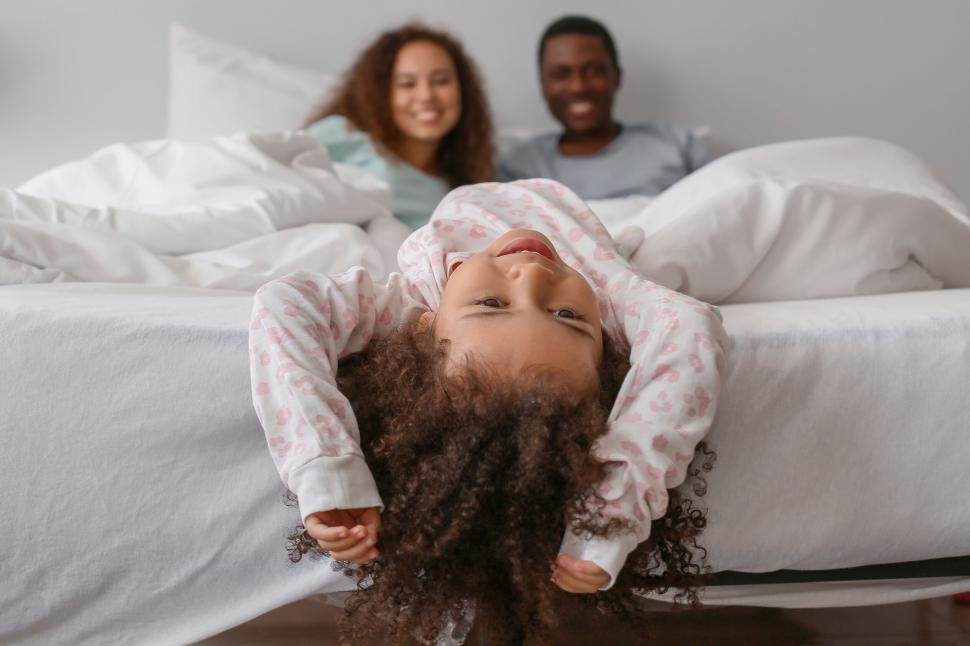 Free Image of Young girl playing upside down on bed 