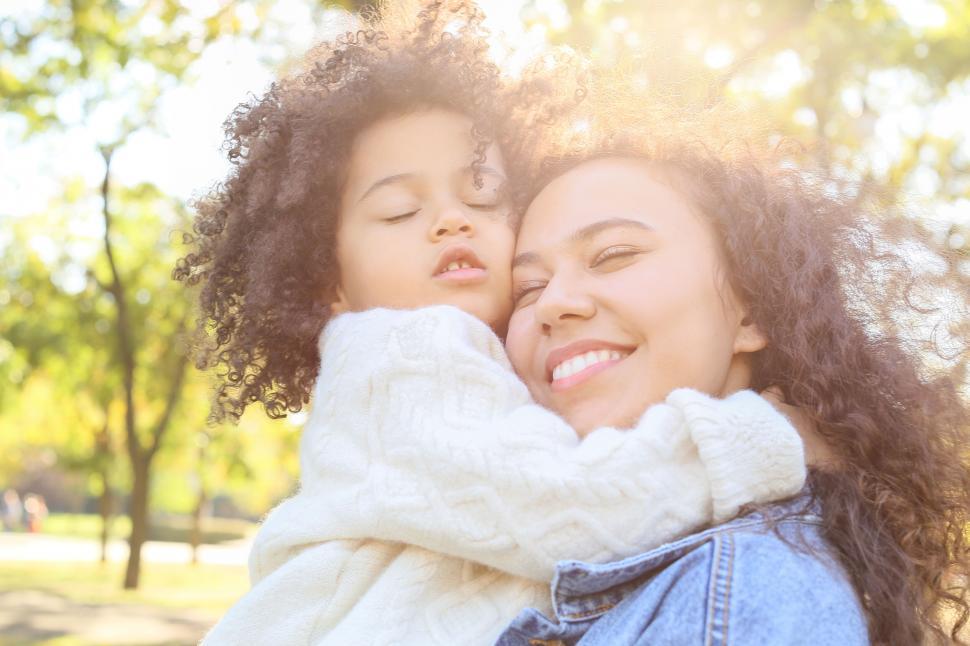 Free Image of Mom embracing daughter in sunlit park 