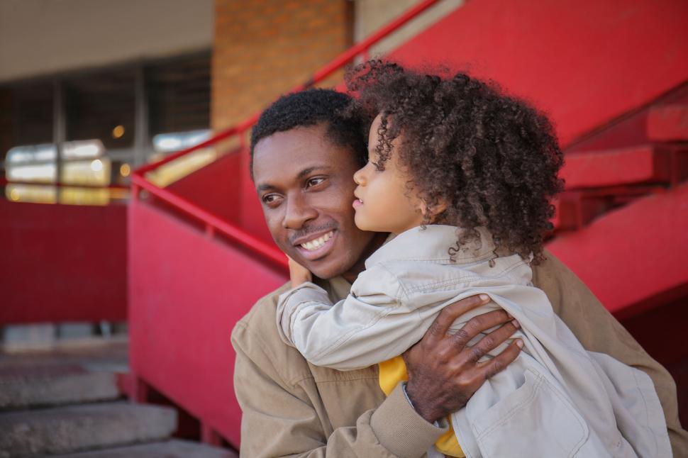 Free Image of Father embracing child with red backdrop 