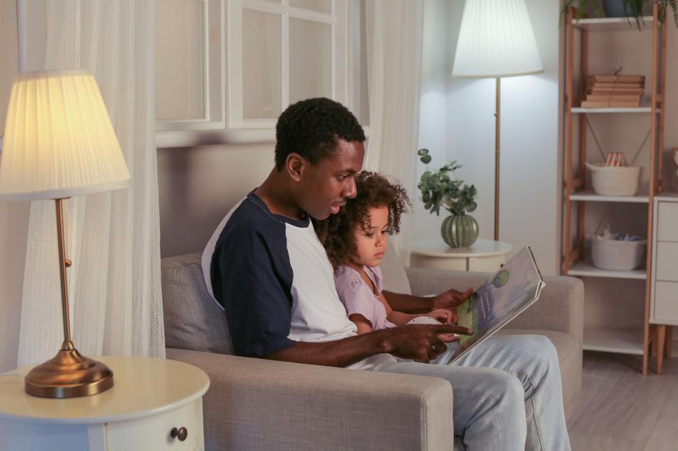 Free Image of Father and child reading book in living room 