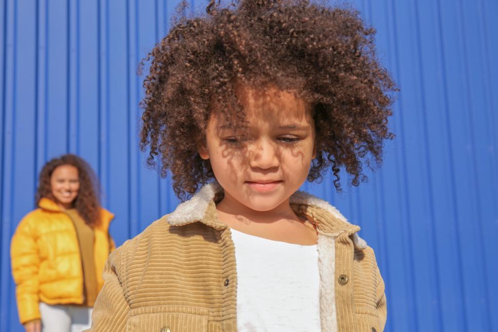 Free Image of Sad child with family in background 
