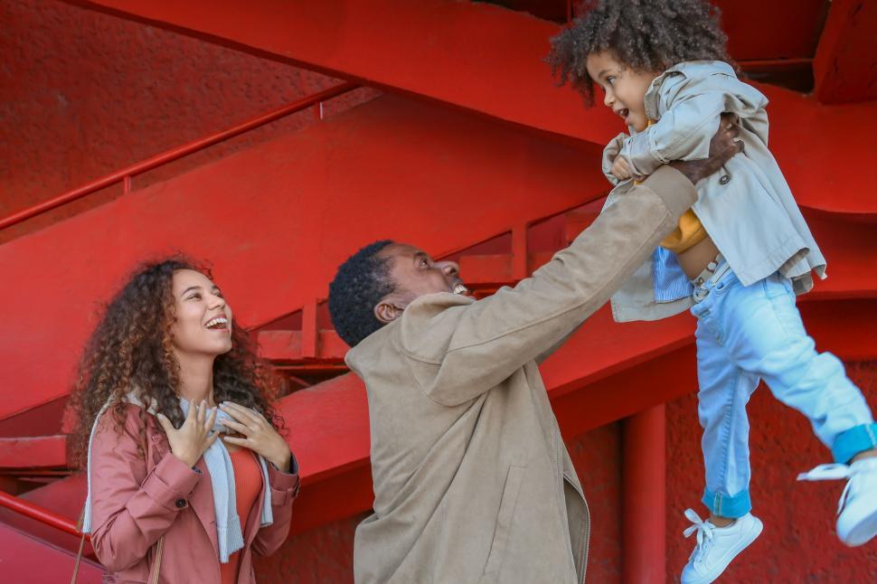 Free Image of Child being lifted by father near red structure 