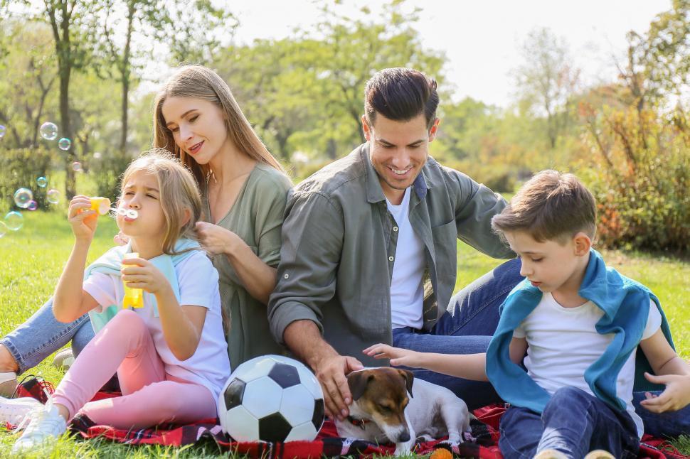 Free Image of Family blowing bubbles dog sitting on picnic 