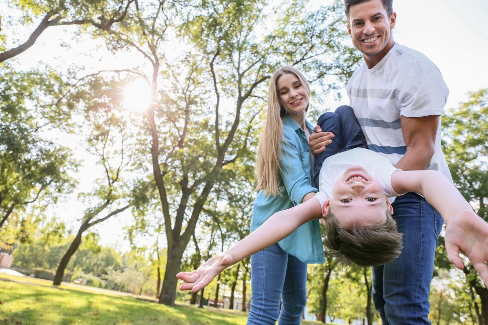 Free Image of Family playing with son in sunlit park 
