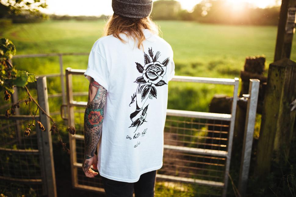 Free Image of Back view of a tattooed person by a fence 