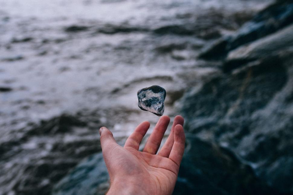 Free Image of Levitating stone above a hand by water 