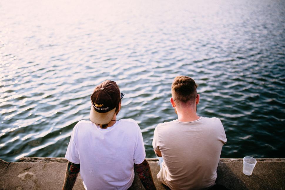 Free Image of Two men sitting and relaxing by the water 