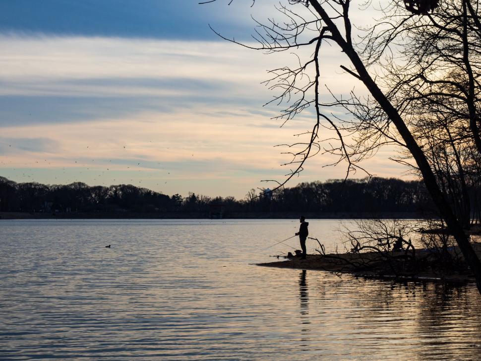 Free Image of Silhouette of a man fishing by a lake 