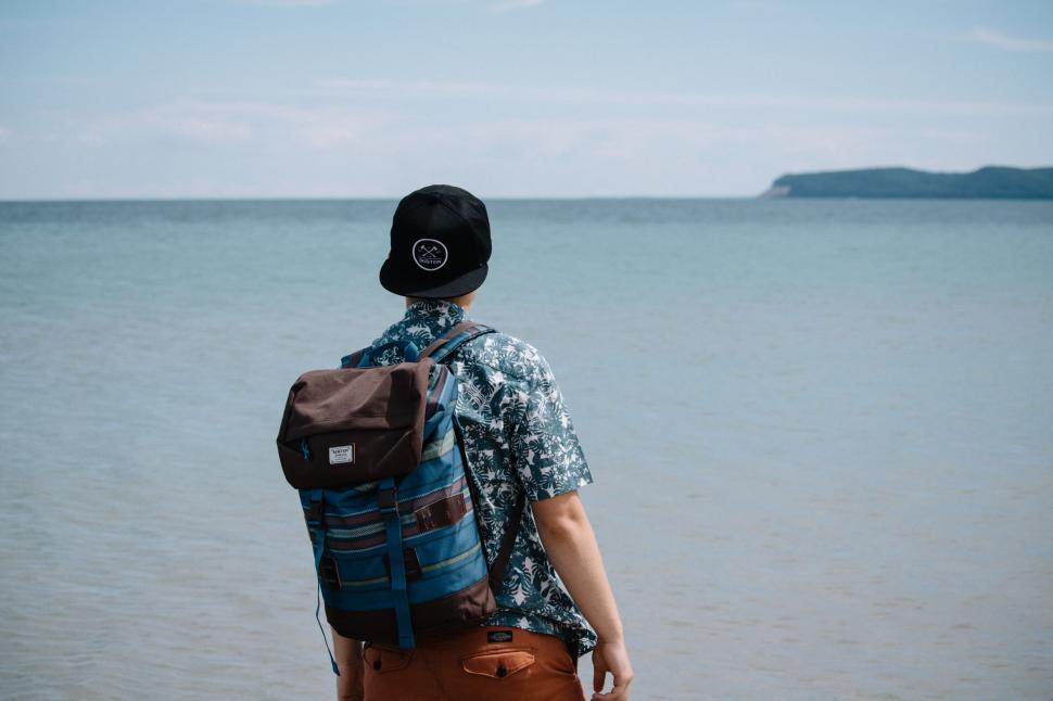 Free Image of Man gazing at sea with mountain backdrop 