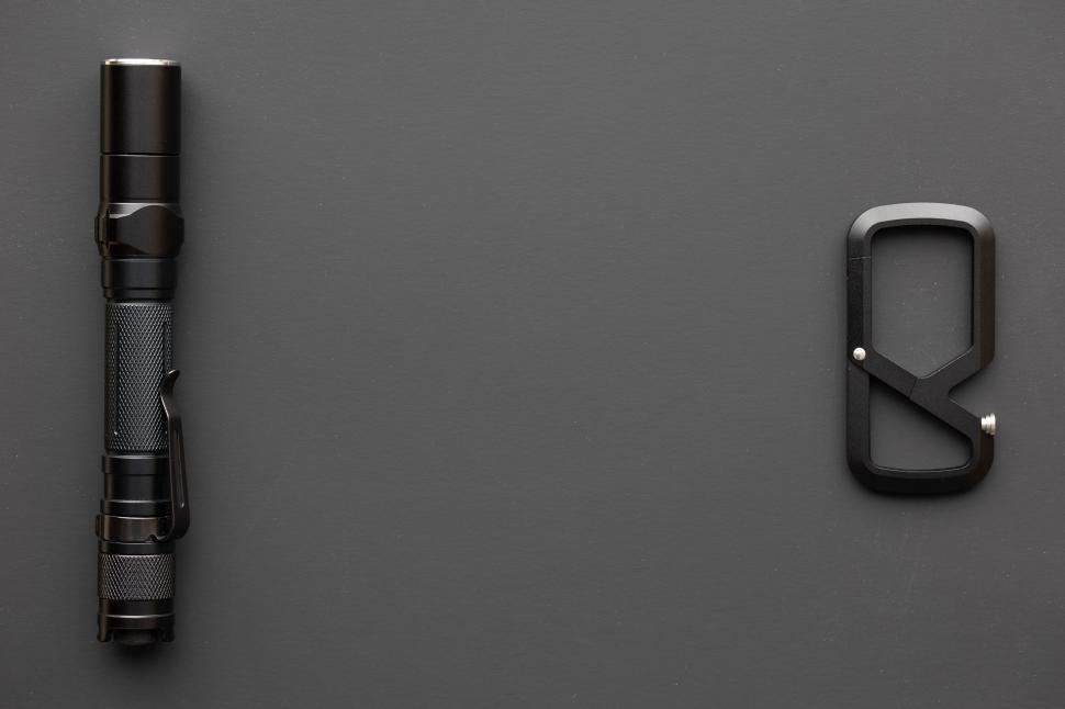 Free Image of Black flashlight and carabiner on dark background 