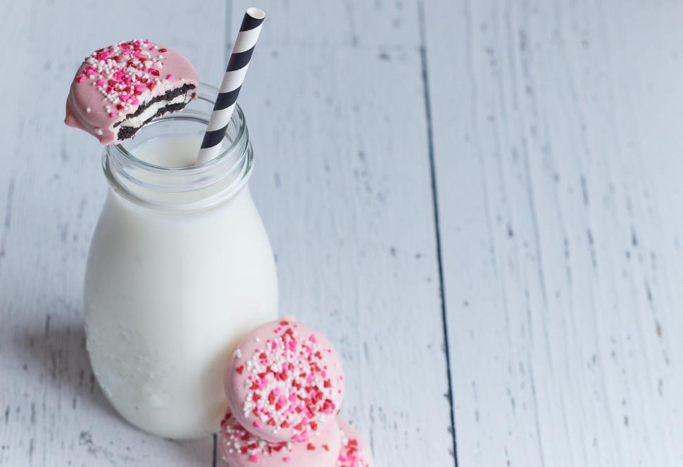 Free Image of Pink donut and milk on a white wooden table 