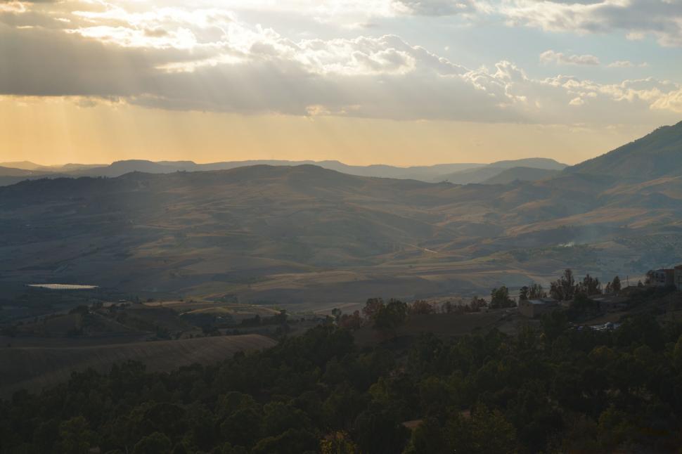 Free Image of Sunset rays over rolling hills 