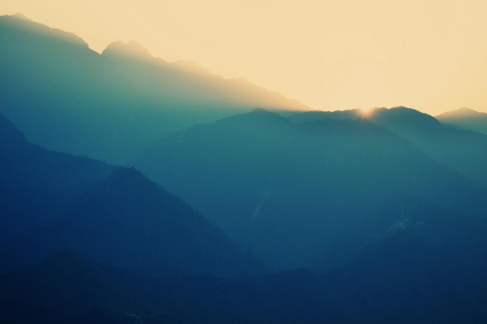 Free Image of Sunrise over mountain layers in blue hues 