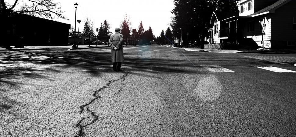 Free Image of Woman standing alone on a sunlit urban street 
