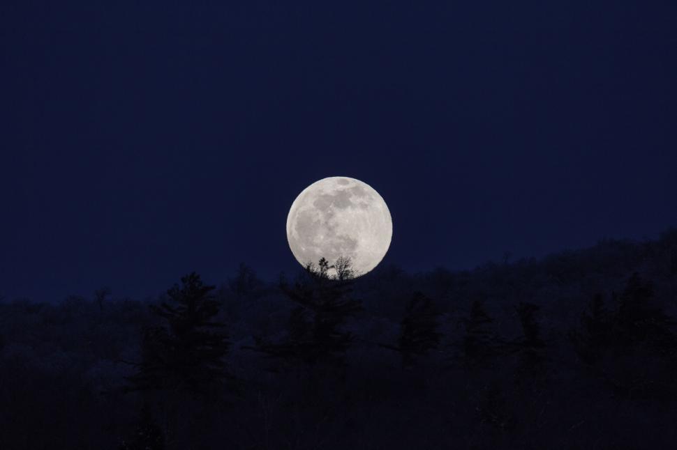 Free Image of Full moon over a forested mountain 