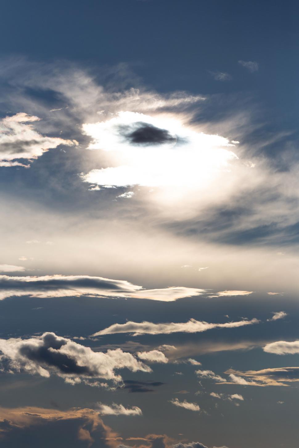 Free Image of Sun piercing through a cloudy blue sky 