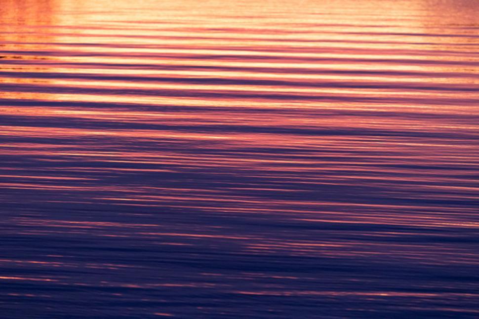 Free Image of Sunset reflecting on calm waterfront 