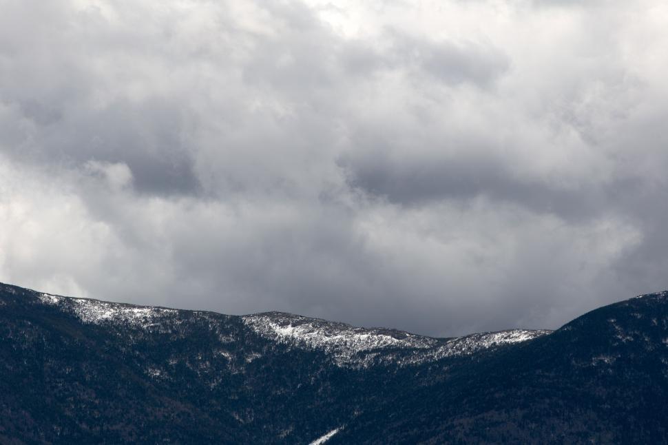 Free Image of Mountain range with snow under cloudy skies 