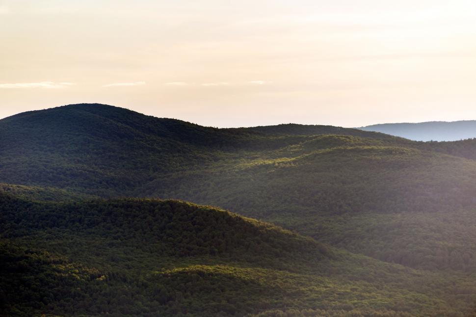Free Image of Sunrise over rolling green hills 