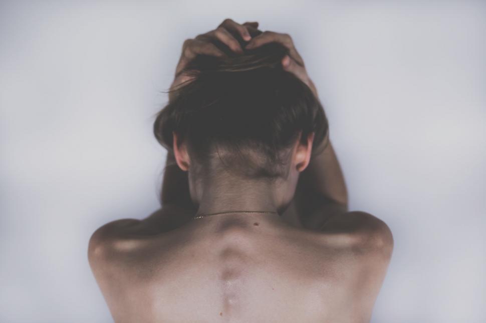 Free Image of Woman holding her hair up against white backdrop 
