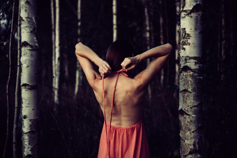 Free Image of Woman standing between birch trees at dusk 