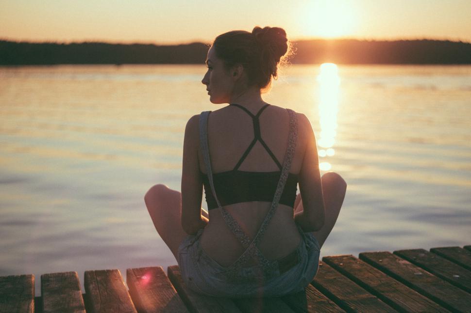 Free Image of Woman meditating by the lake at sunset 