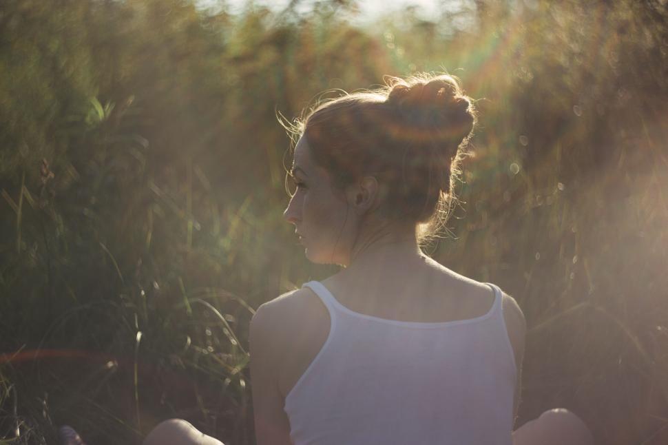 Free Image of Backlit woman sitting in grassy field 
