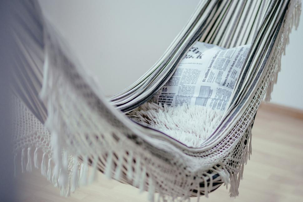 Free Image of Newspaper resting on a comfy woven hammock 