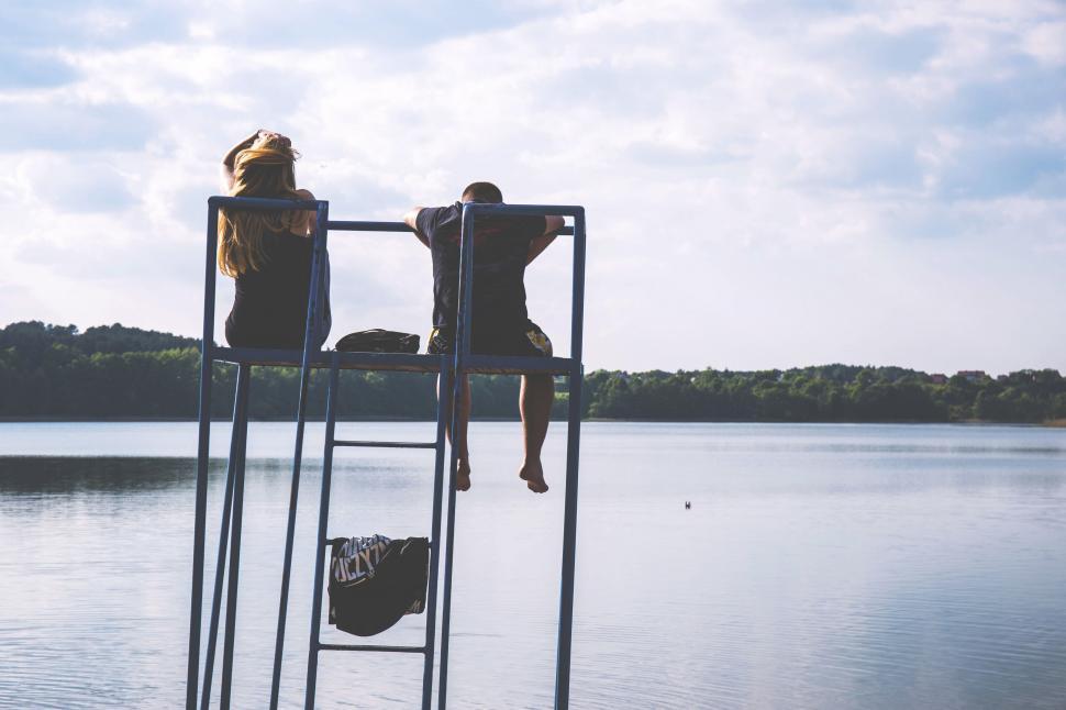 Free Image of Two friends enjoying a tranquil lakeside view 