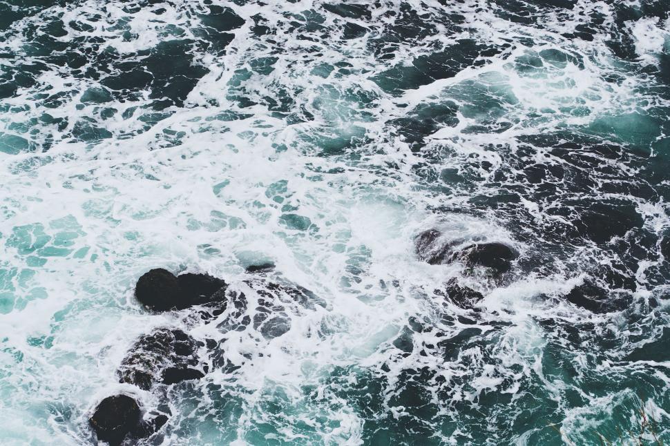 Free Image of Aerial view of ocean waves crashing on rocks 
