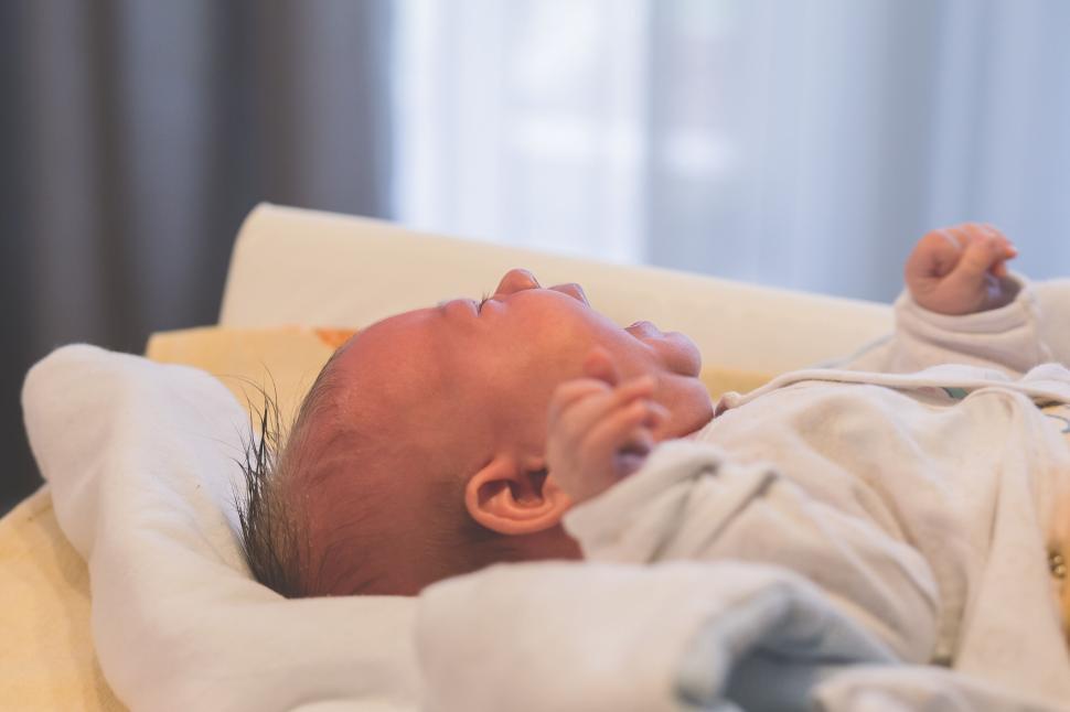 Free Image of Infant resting on a couch under a blanket 