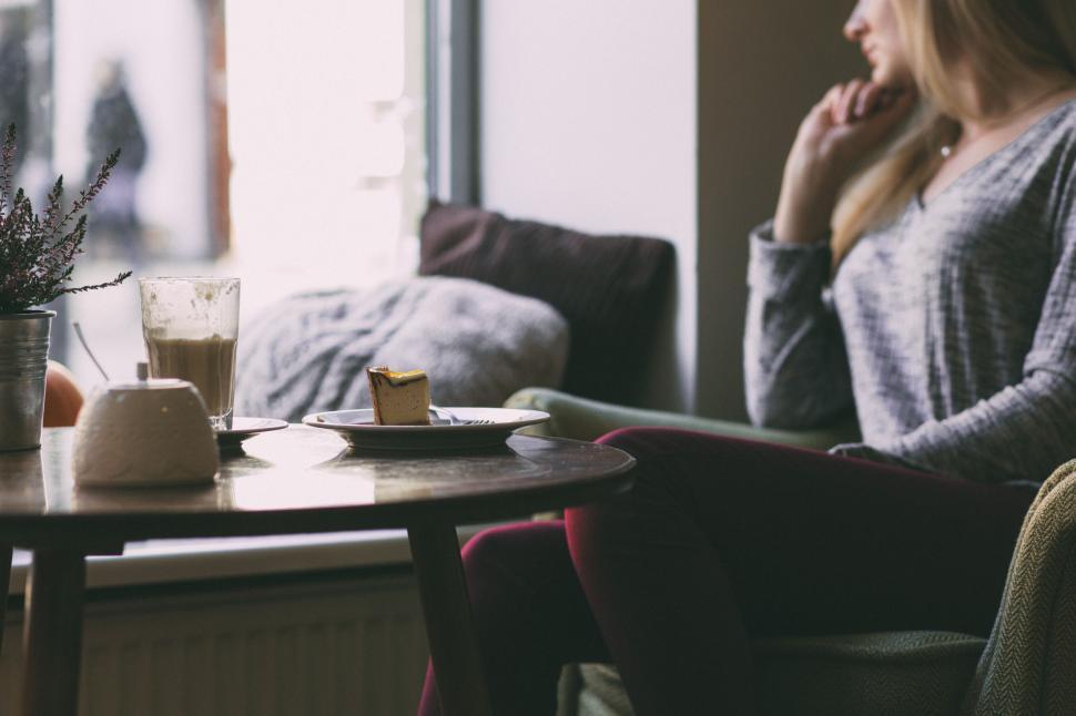 Free Image of Cozy cafe scene with a woman enjoying a drink 