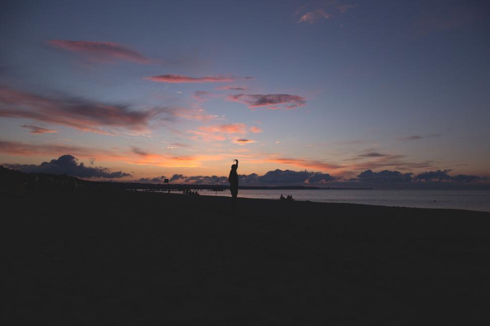 Free Image of Silhouette of a person on the beach at dusk 