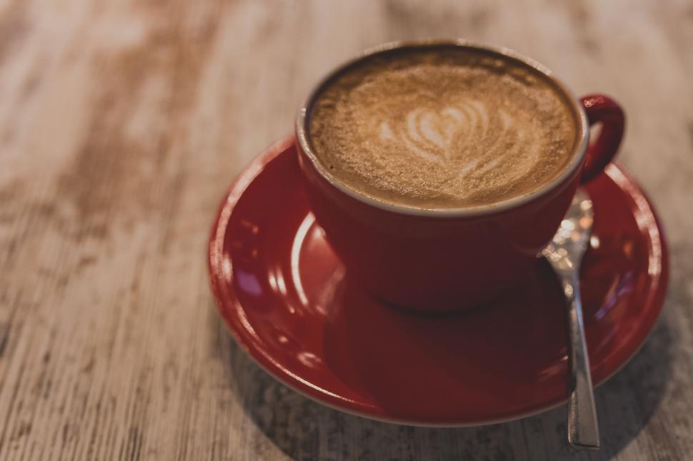Free Image of Red cup of coffee with artistic foam design 