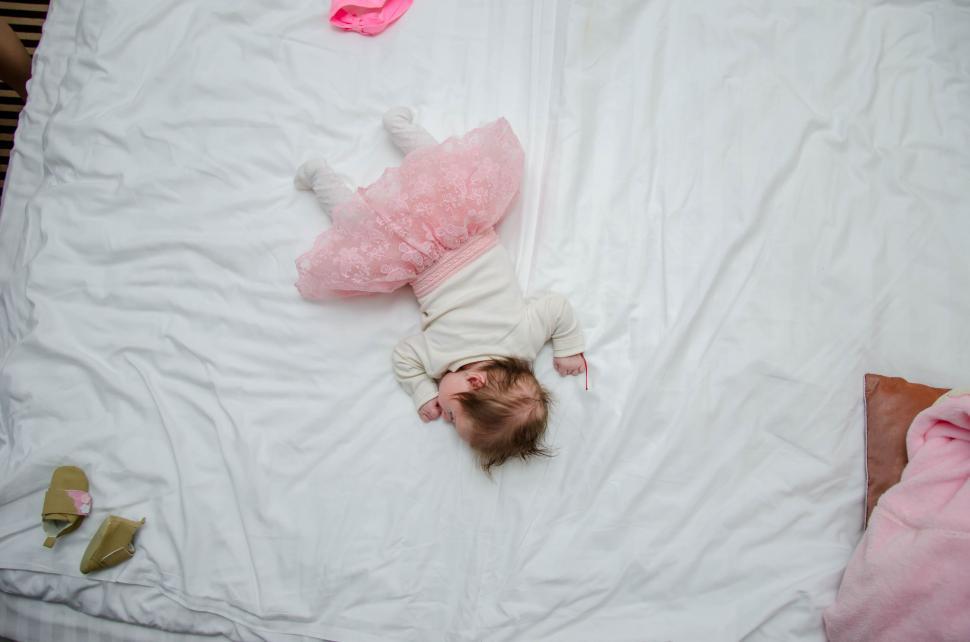 Free Image of Toddler in a pink tutu lying on a bed 