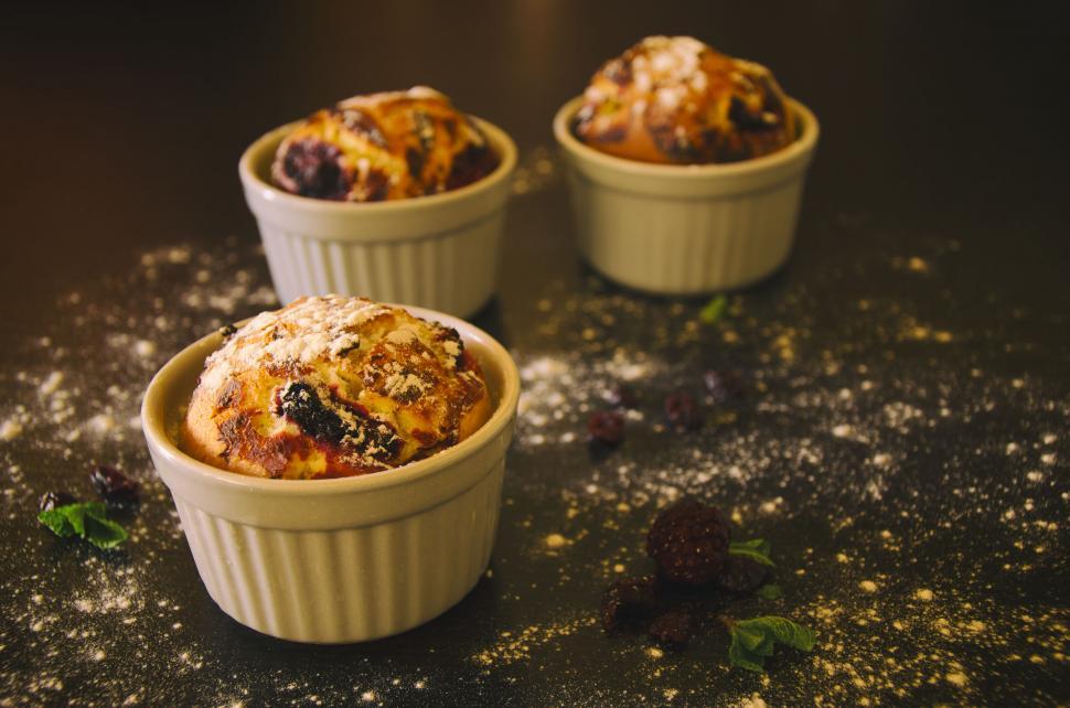 Free Image of Two pastries in ceramic dishes on dark surface 