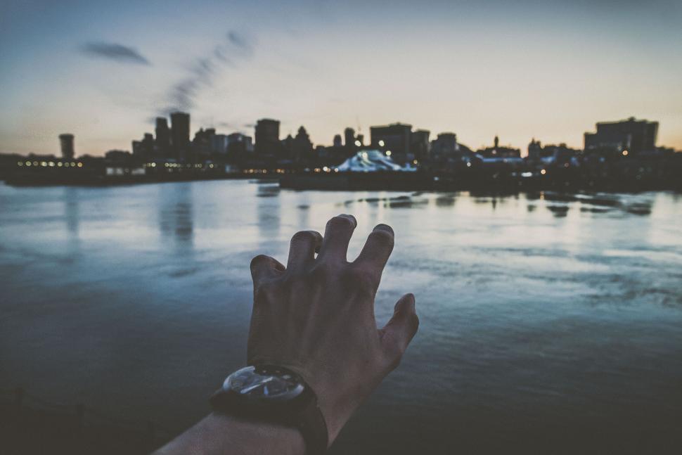 Free Image of Hand reaching out towards a city skyline 