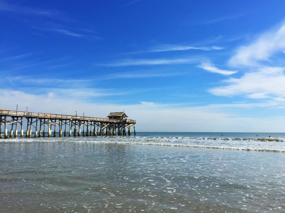 Free Image of Sunny pier scene with gentle ocean waves 