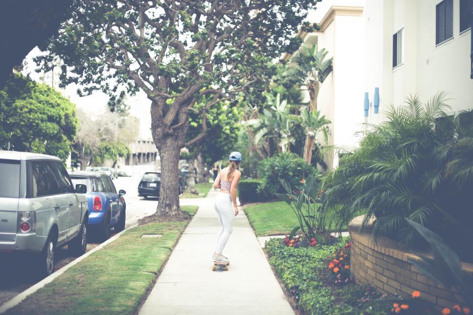 Free Image of Woman skateboarding down a suburban street 