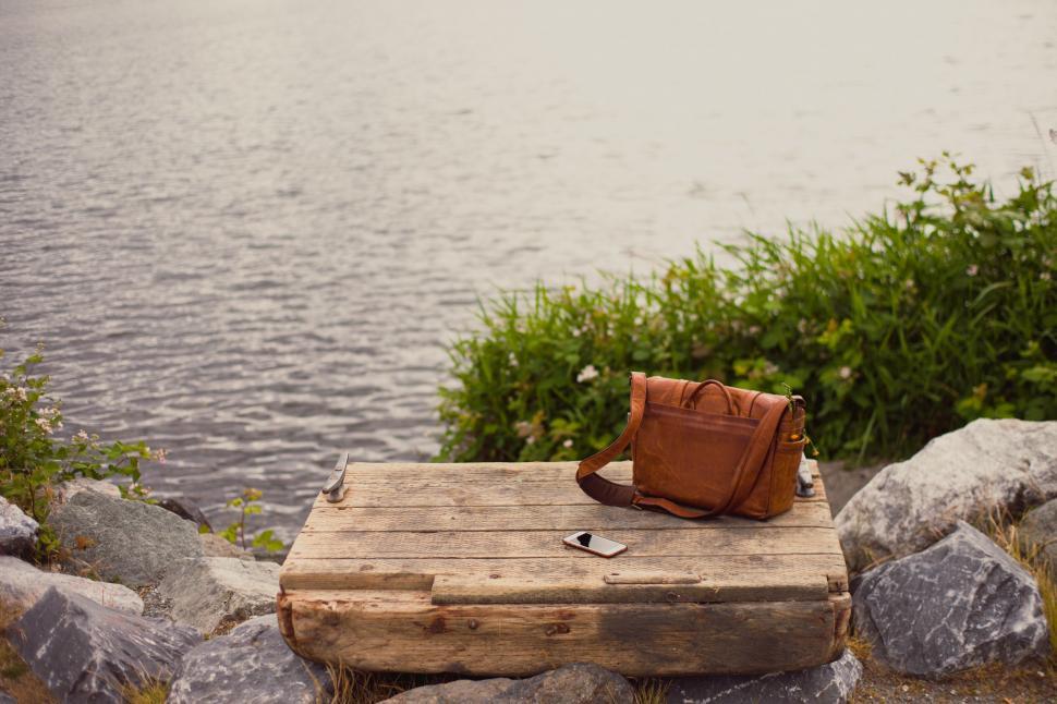 Free Image of Rustic riverside scene with a leather bag 